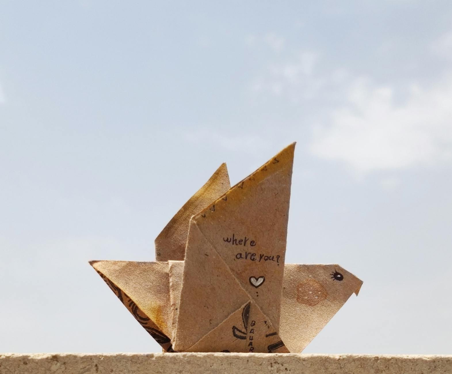 Papierowy ptak z napisem where are you na tle czystego nieba