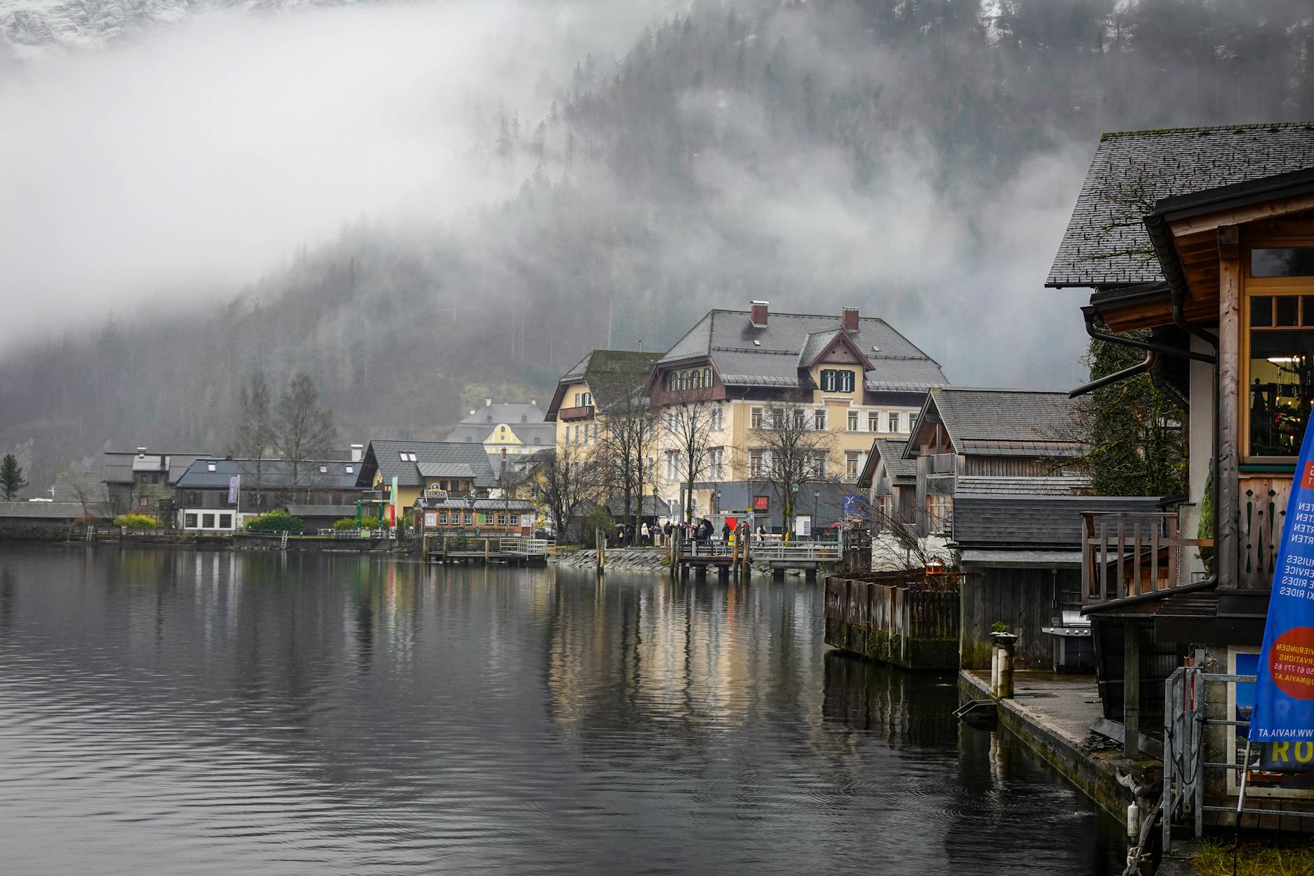 Zimowa alpejska wioska nad jeziorem spowita mgłą