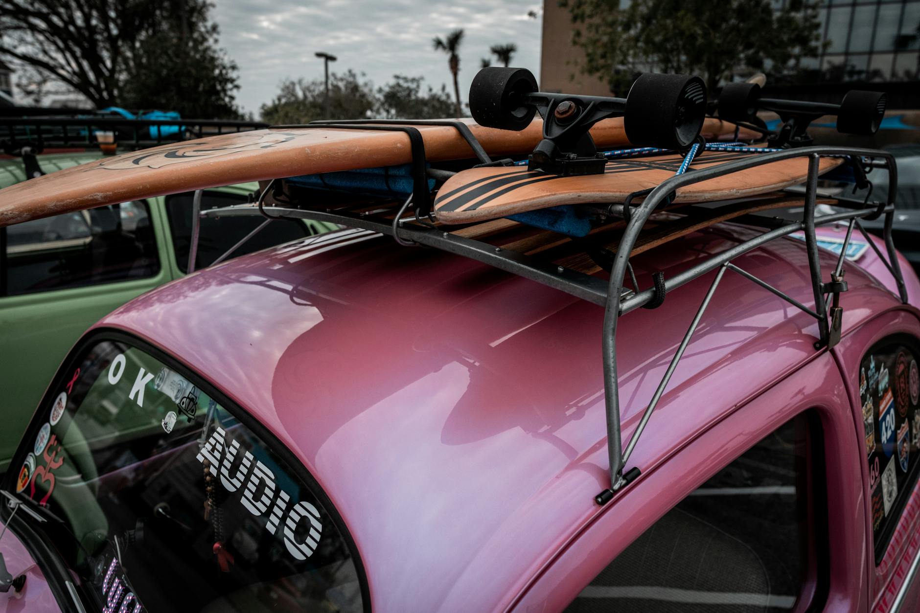 Różowy garbus z deskorolką na dachu zaparkowany na zewnątrz