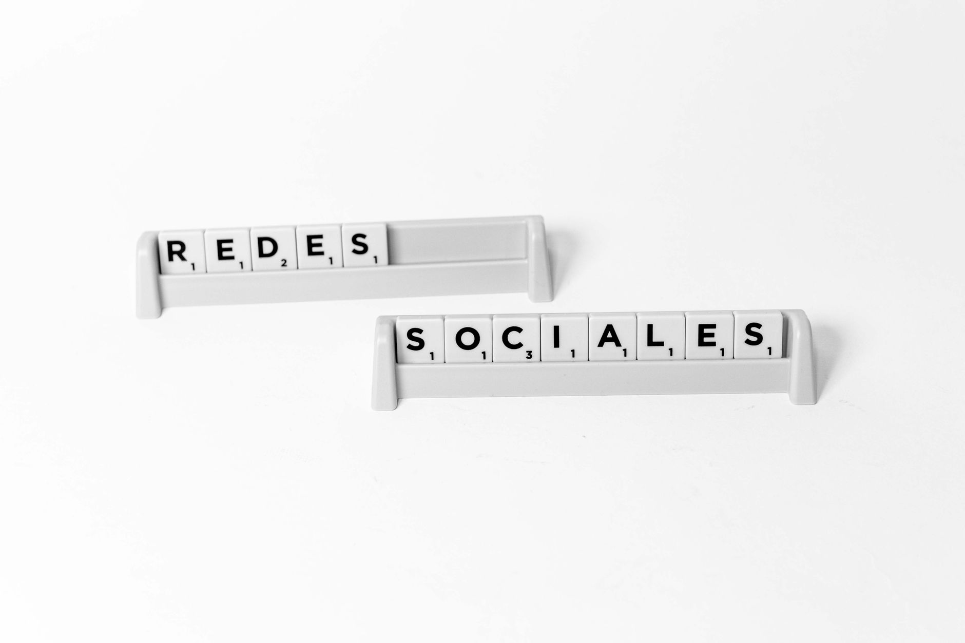 Kafle Scrabble układające się w napis Redes Sociales na białym tle